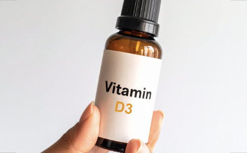 Flasche mit Vitamin D3 von Hand gehalten